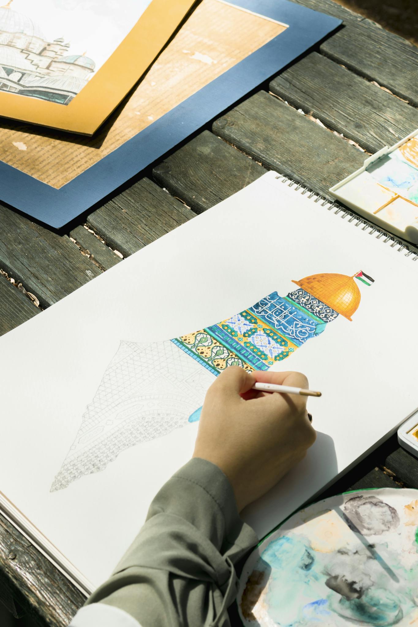 A person drawing a vibrant architectural sketch outdoors on a sunny day.