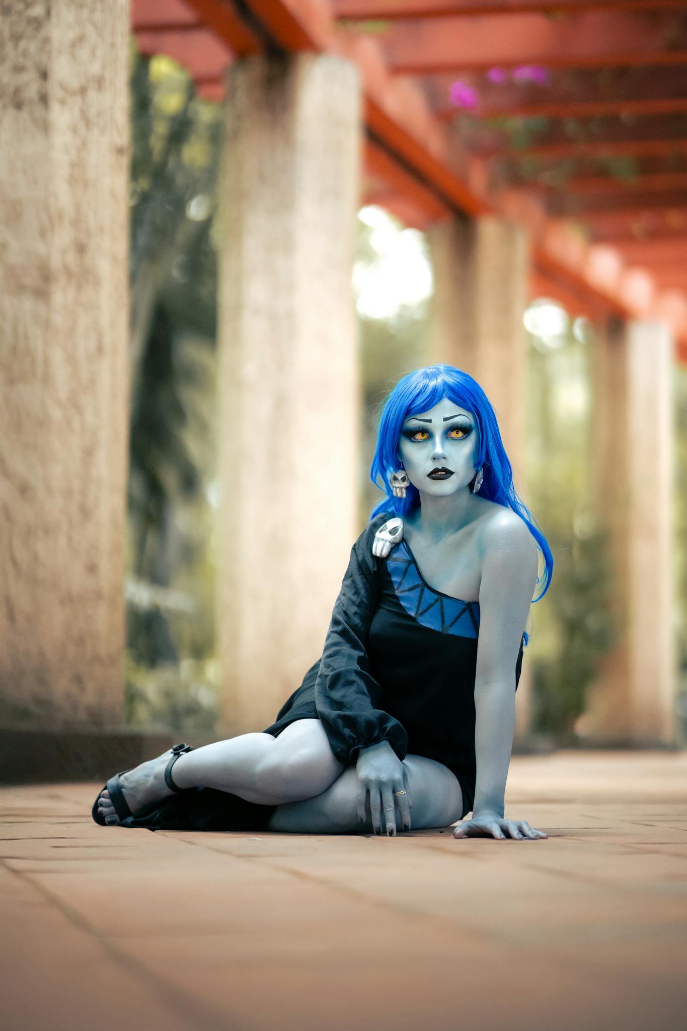A striking cosplay character posing in a vibrant outdoor garden setting in Mexico City.