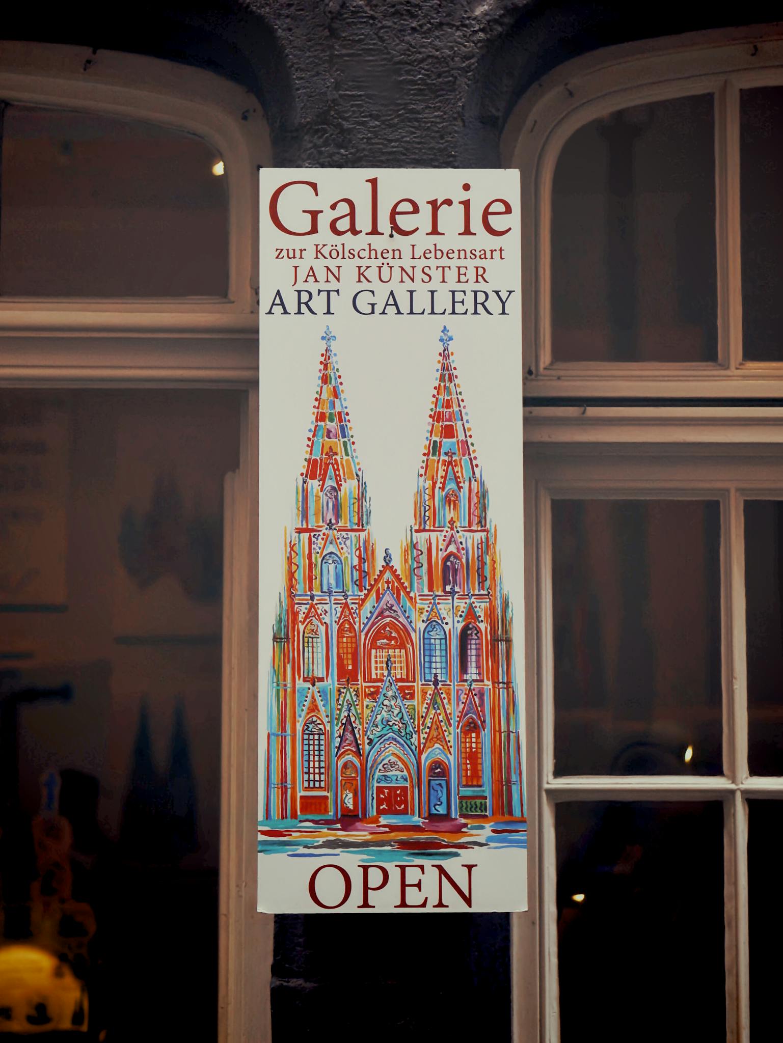 A vibrant art gallery sign depicting a colorful illustration of a cathedral facade.