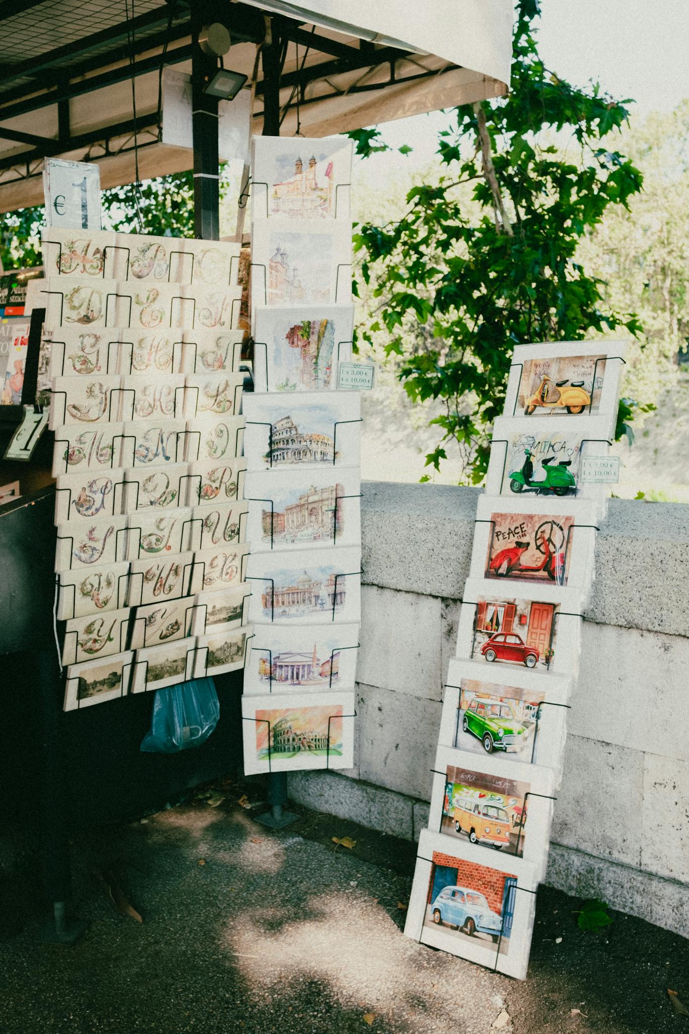 Colorful paintings displayed at an outdoor art stall under natural light.