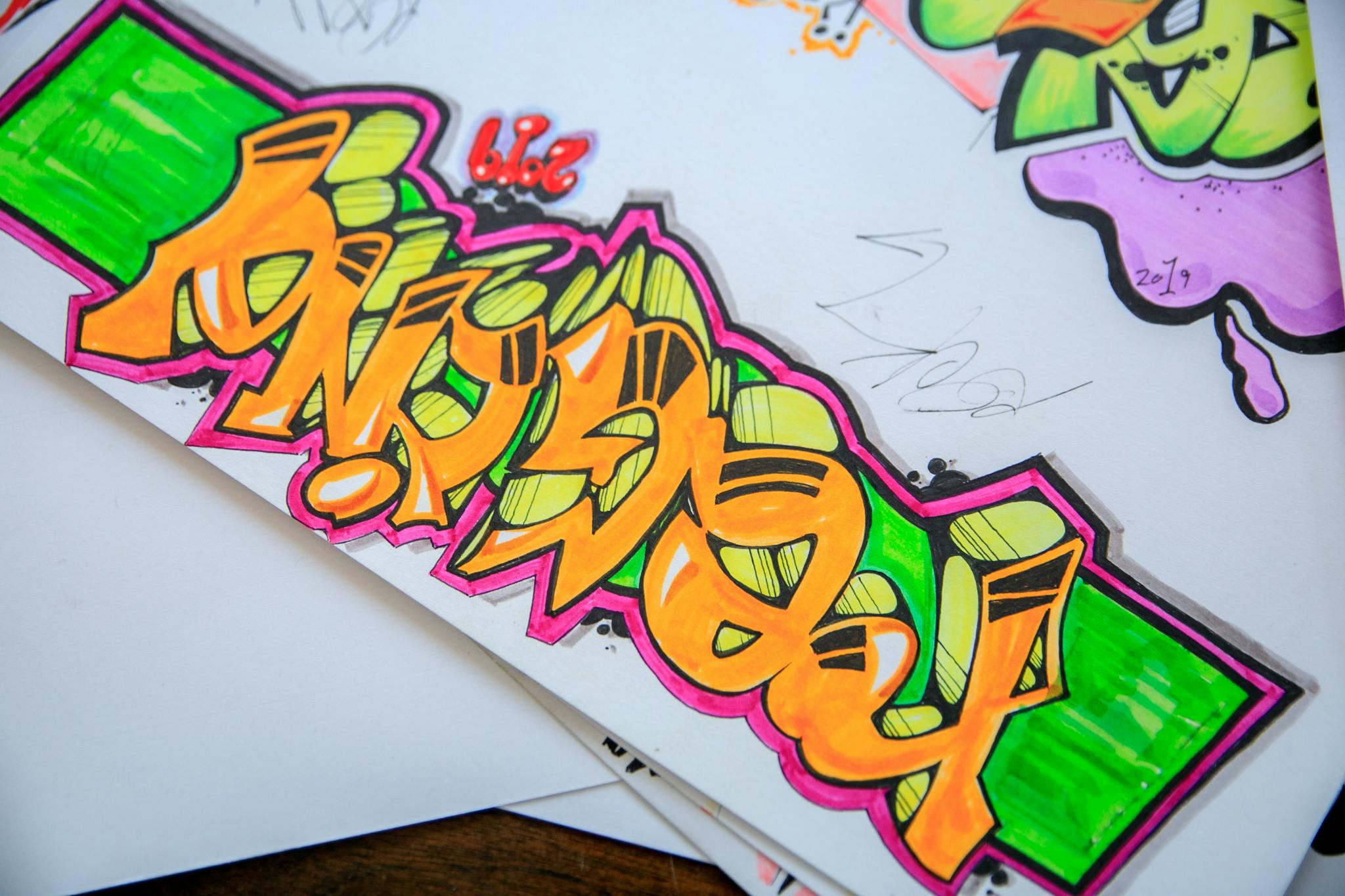 Colorful street art graffiti drawn on paper with vibrant colors and bold designs.